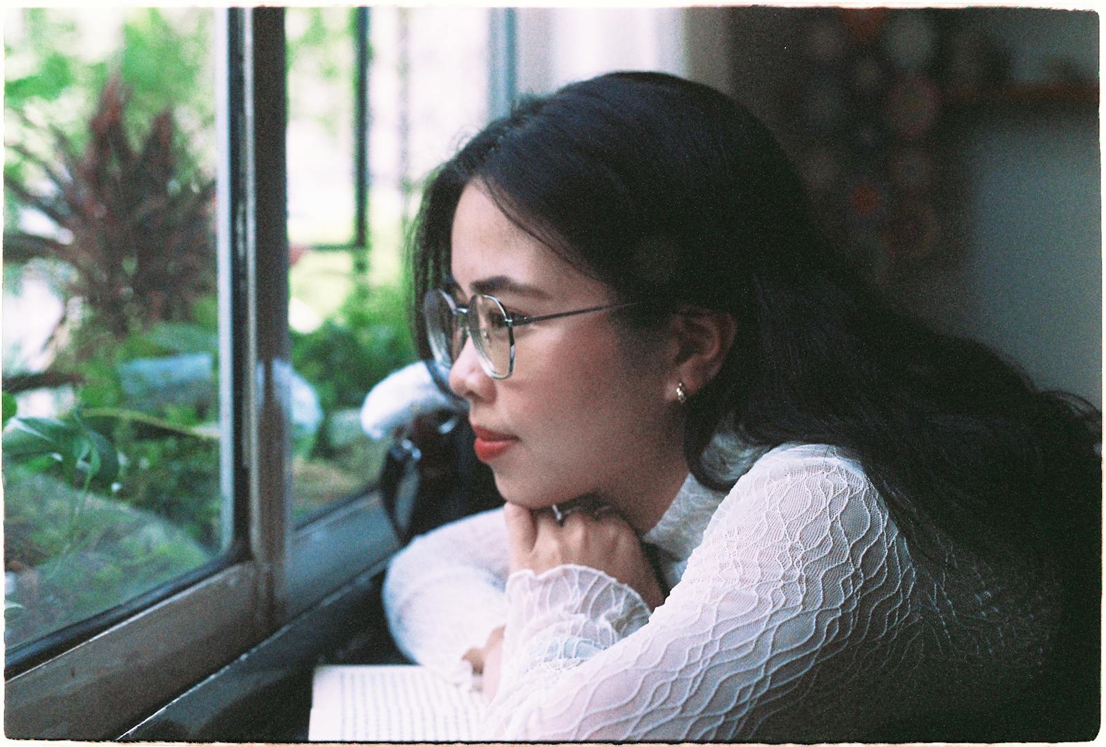 Woman gazing thoughtfully out a window, reflecting quietly