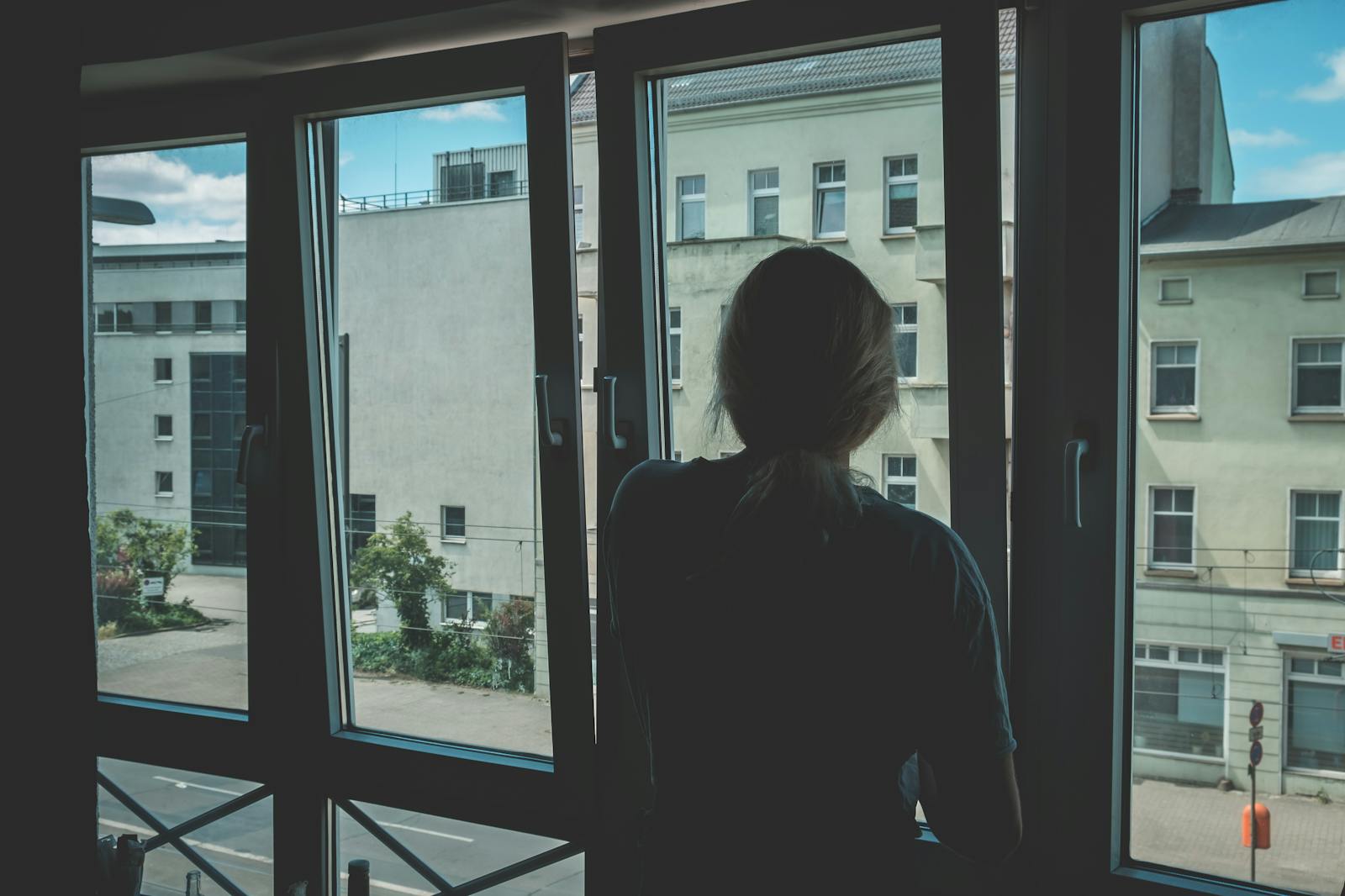 A young person sitting by a window, looking out thoughtfully