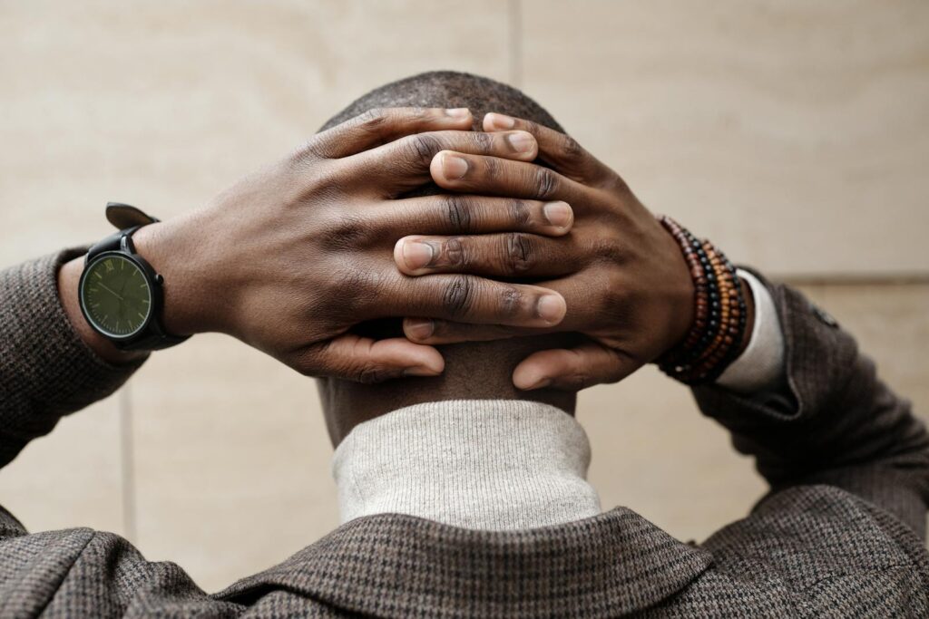Back view of an adult with hands on head — rumination and the “what if” loop